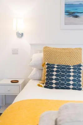 a bedroom with a bed with yellow and blue pillows at Kota Restaurant & Rooms in Porthleven