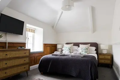 a bedroom with a bed and a flat screen tv at Kota Restaurant & Rooms in Porthleven