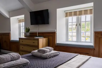 a bedroom with a bed and a tv on the wall at Kota Restaurant & Rooms in Porthleven