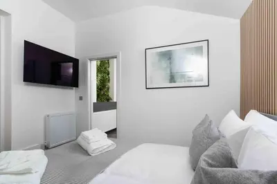 a white bedroom with a bed and a flat screen tv at Stunning new fully renovated flat in Marazion in Marazion