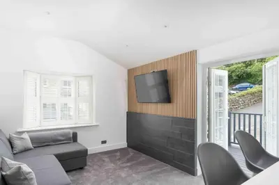 a living room with a couch and a tv on a wall at Stunning new fully renovated flat in Marazion in Marazion
