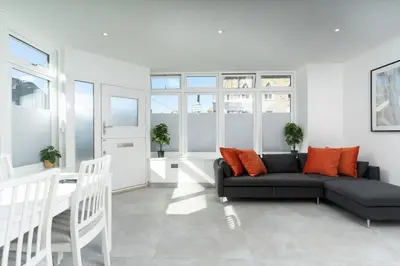a living room with a black couch and orange pillows at Stunning new 1 bed apartment in Marazion. in Marazion