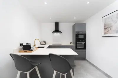 a kitchen with a white counter and two chairs at Stunning new 1 bed apartment in Marazion. in Marazion