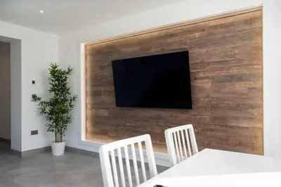 a flat screen tv on a wooden wall with a table and chairs at Stunning new 1 bed apartment in Marazion. in Marazion