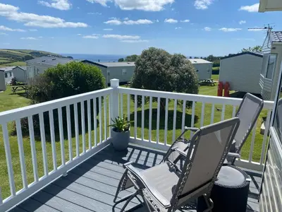 two chairs on a deck with a view of the ocean at Gannets Rest - Spacious Static Caravan with Sea Views in Polperro