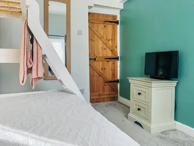 a bedroom with a bunk bed and a tv at The Annex At Tenniside in Perranporth