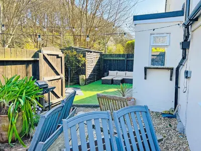 a backyard with blue chairs and a fence at The Annex At Tenniside in Perranporth