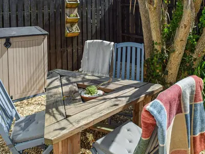 a picnic table and a chair with a plant on it at The Annex At Tenniside in Perranporth