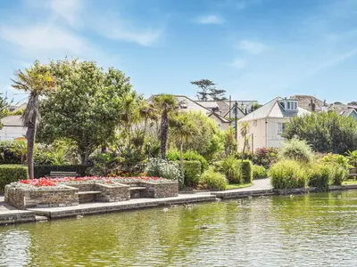 a park with a pond with flowers and houses at The Annex At Tenniside in Perranporth