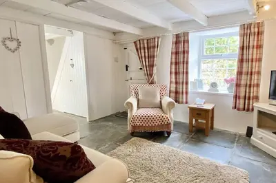 a living room with a couch and a chair and a tv at Stable Cottage in Delabole