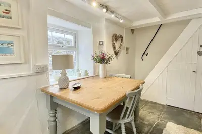 a dining room table with a lamp and flowers on it at Stable Cottage in Delabole