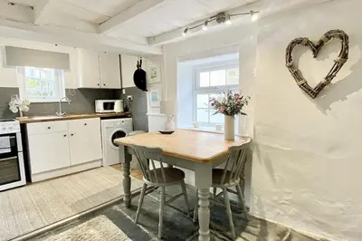 a kitchen with a table with a heart on the wall at Stable Cottage in Delabole