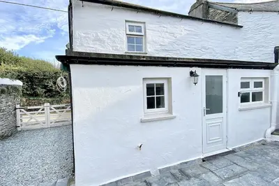 a white house with a white door and a fence at Stable Cottage in Delabole