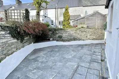 a stone walkway in front of a brick wall at Stable Cottage in Delabole
