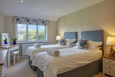 two beds in a room with two windows at Meadowside in Saint Mawes
