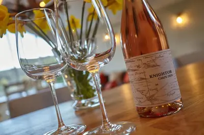 a bottle of wine and two glasses on a table at Meadowside in Saint Mawes