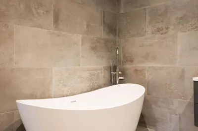 a white bath tub in a bathroom with tiles at Breakers View in Wadebridge