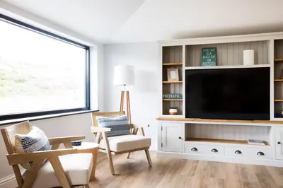 a living room with a flat screen tv on a white entertainment center at Breakers View in Wadebridge