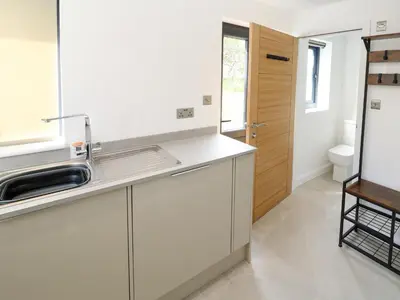 a white kitchen with a sink and a toilet at Tredarn in Hayle