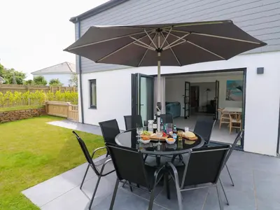 a patio with a table with an umbrella at Tredarn in Hayle