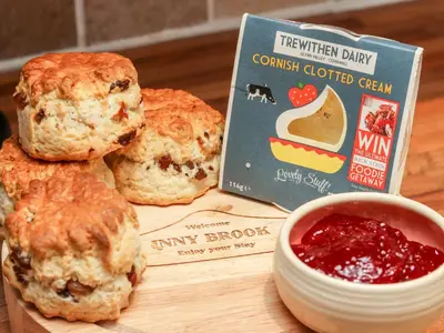 a cutting board with a bagel and a box of jam at Inny Brook Cottage in Camelford