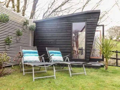 a couple of chairs and a tiny house at Inny Brook Cottage in Camelford