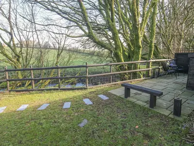 a bench sitting in the grass next to a fence at Inny Brook Cottage in Camelford