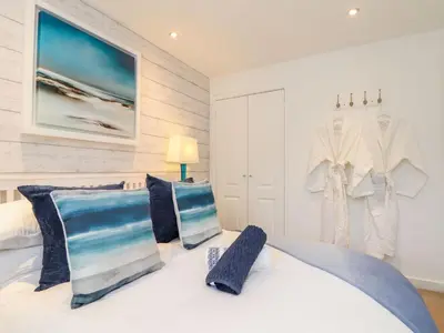 a bedroom with a large white bed with blue pillows at Inny Brook Cottage in Camelford