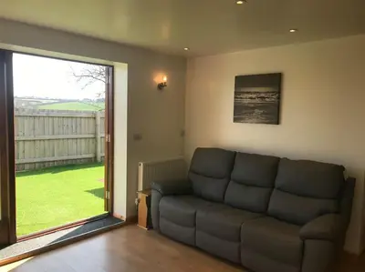 a living room with a couch and a large window at Hendra Retreat Owls Roost Cottage North Cornwall in Camelford