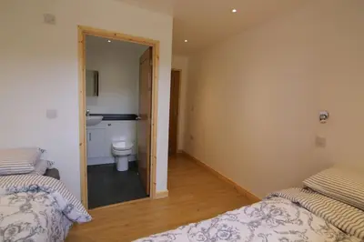 a bedroom with two beds and a bathroom with a toilet at Hendra Retreat Owls Roost Cottage North Cornwall in Camelford