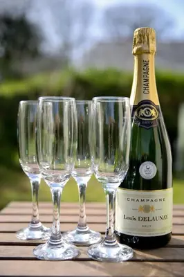 four wine glasses and a bottle of champagne on a table at Hendra Retreat Owls Roost Cottage North Cornwall in Camelford