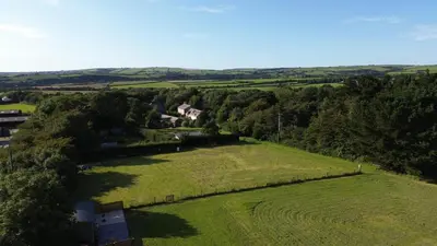 an aerial view of a house in a green field at St. Kew Shepherd Huts in Wadebridge