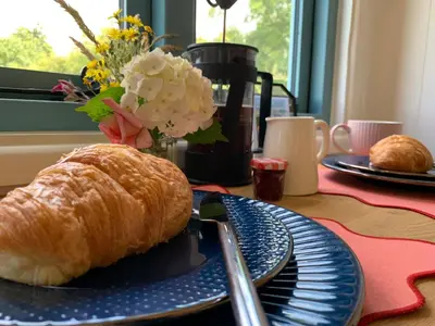 a blue plate with a croissant on a table at St. Kew Shepherd Huts in Wadebridge