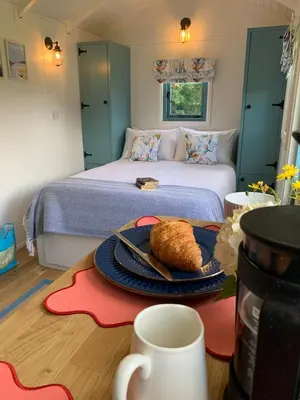 a bedroom with a bed with a plate of food on a table at St. Kew Shepherd Huts in Wadebridge