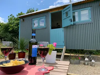 a table with wine glasses and a bottle of wine at St. Kew Shepherd Huts in Wadebridge