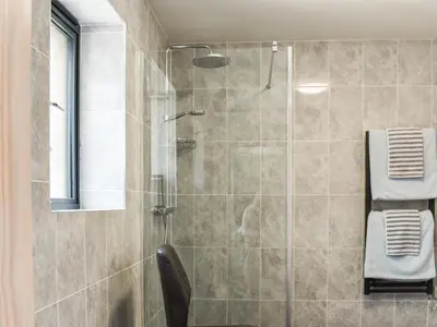 a bathroom with a glass shower with a chair at Pentarow in Constantine