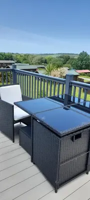 a patio table and chairs on a deck with the ocean at Lake view in Newquay