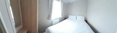 a white bed in a room with a window at Lake view in Newquay