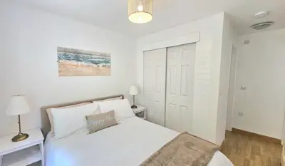 a white bedroom with a bed and a door at 14 Granite Henge in Looe
