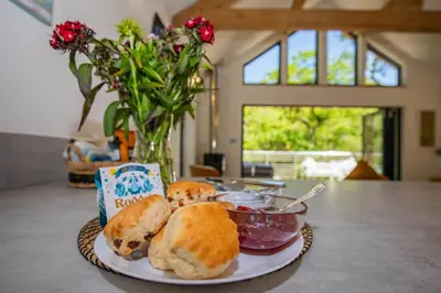a plate of food on a table with a bowl of bread at Tresillian Lodge Waterfront, Forest, Hot tub,Sauna in Truro
