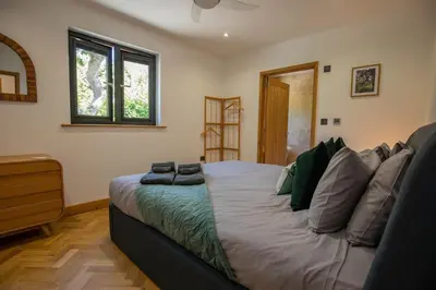 a bedroom with a large bed and a window at Tresillian Lodge Waterfront, Forest, Hot tub,Sauna in Truro