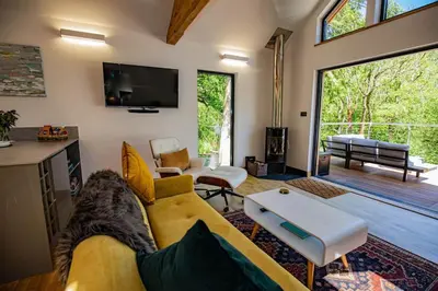 a living room with a yellow couch and a tv at Tresillian Lodge Waterfront, Forest, Hot tub,Sauna in Truro