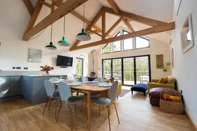a kitchen and living room with a table and chairs at Tresillian Lodge Waterfront, Forest, Hot tub,Sauna in Truro