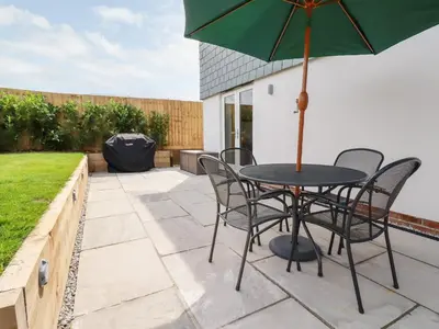 a table with chairs and an umbrella on a patio at Chynoweth House in Newquay