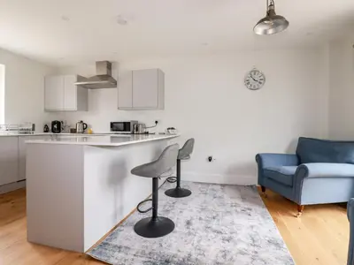 a kitchen with a bar stool and a blue couch at Chynoweth House in Newquay