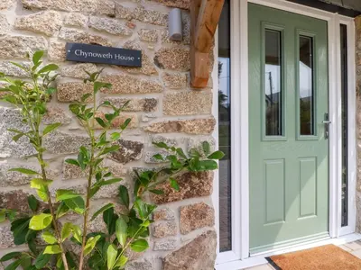 a green door on a stone house with a plant at Chynoweth House in Newquay