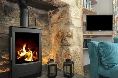 a fireplace with two candles in front of a stone wall at Stargazy Cottage in Penzance