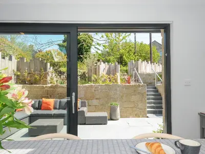 an open patio door with a couch and chairs at Stargazy Cottage in Penzance