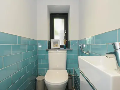 a blue tiled bathroom with a toilet and a sink at Stargazy Cottage in Penzance