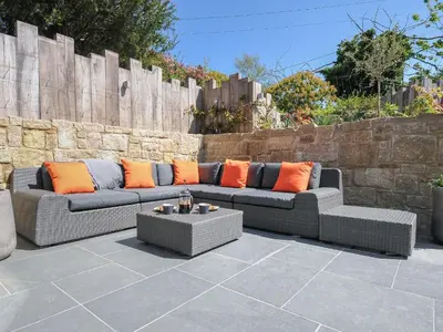 a patio with two couches and a table at Stargazy Cottage in Penzance